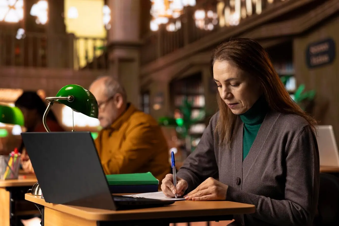 Взрослая женщина транскрибирует учебную работу и изучает материалы для своей университетской степени.